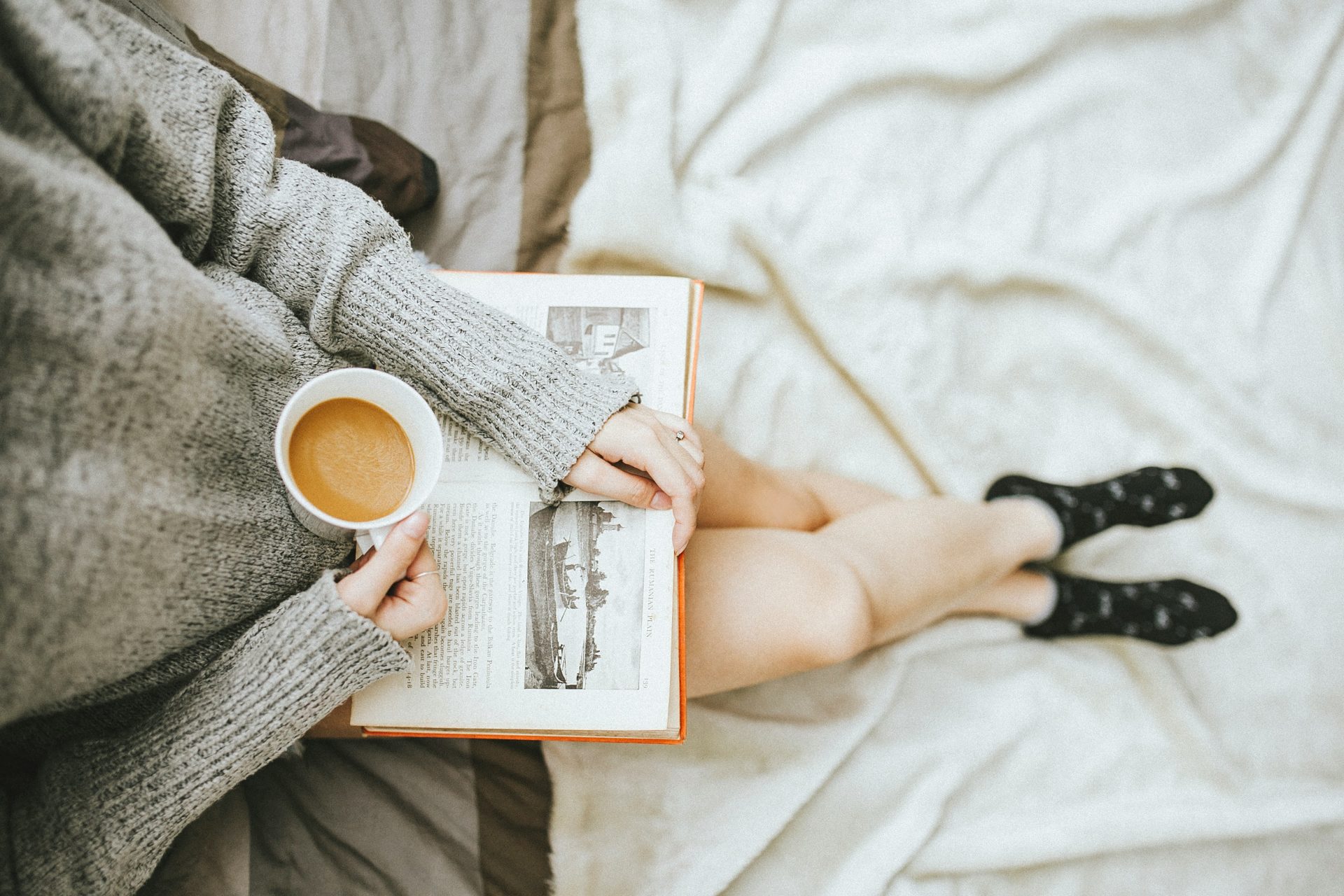 woman reading a book with a hot drink