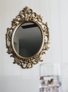 a gold antique oval shaped mirror on a white wall